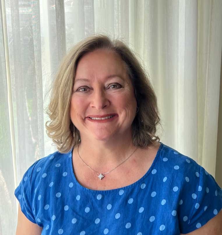 Portrait of a smiling woman in front of  sheer drapes